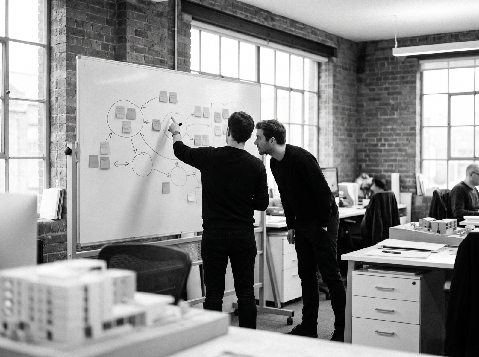 Two strategists discussing positioning at a whiteboard